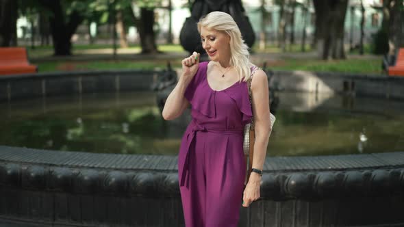 Cheerful Smiling Woman Making Wish Throwing Coin in Fountain in Park alt