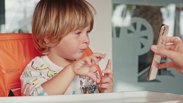 Portrait of a Playful Fairhaired Boy Waiting for His Breakfast at Home alt
