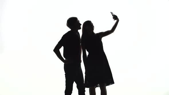 Silhouettes of Man and Woman Take a Selfie in the Studio alt