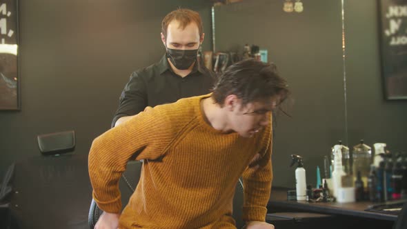 A Young Man with Wet Hair Sits in the Chair in Barbershop alt