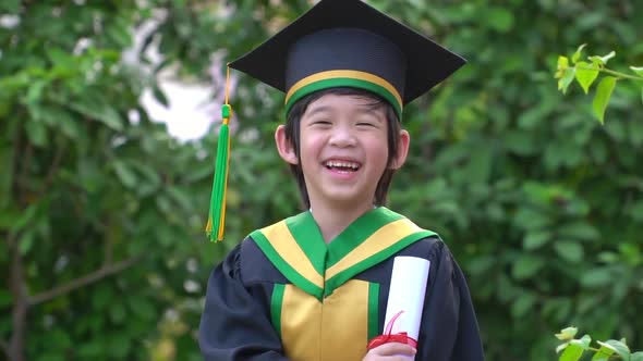Happy Asian Child In Graduation Gowns Holding A Certificate alt