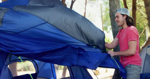 Happy man setting up tent in park 4k alt