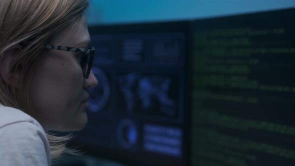 Caucasian female cyber policewoman sitting in darkness in front of computer and working alt