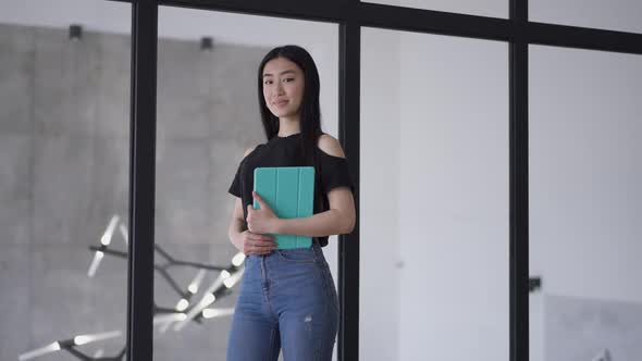 Portrait of Successful Gorgeous Asian Businesswoman Posing in Office Holding Tablet alt