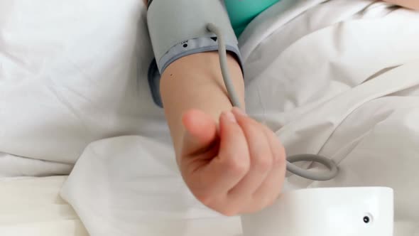 Closeup  Video of Sick Woman Lying in Bed and Wearing Digital Tonometer on Hand alt