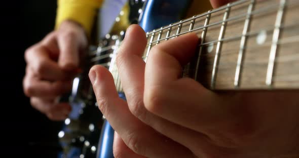 Male Guitarist Playing Fingerpicking with a Plectrum on a Blue Electric Guitar