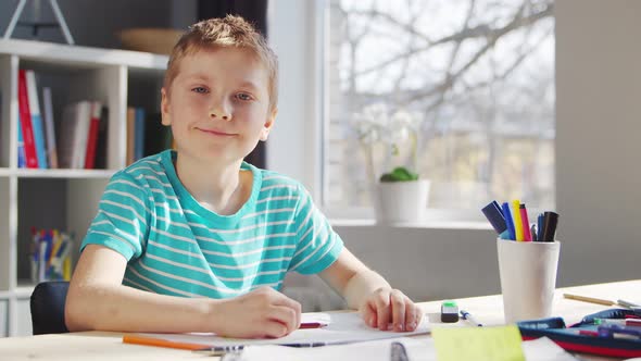 Boy is Doing  Homework at the Table. Cute Child is Learning at Home. alt