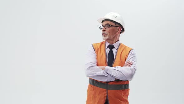Adult man engineer in a working uniform and helmet puts hands on chest and looks to the side. alt
