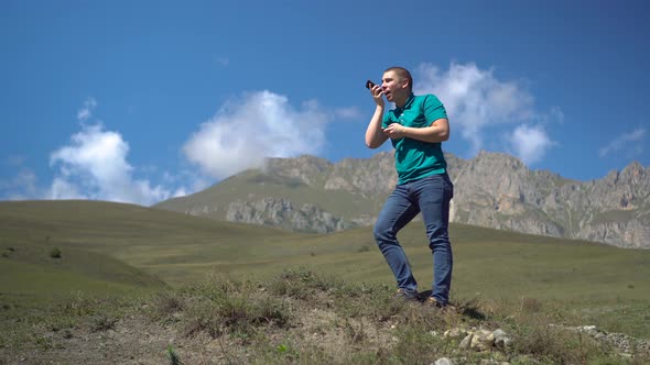 A Young Man Is Looking for a Cellular Network in the Caucasus Mountains. The Man Is Talking on the alt