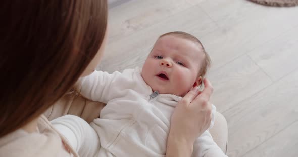 A Young Mother Holds A Newborn Baby On Her Lap And Gently Caresses Her Face. Maternal Care