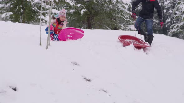 Kids sledding down snow covered hill in winter