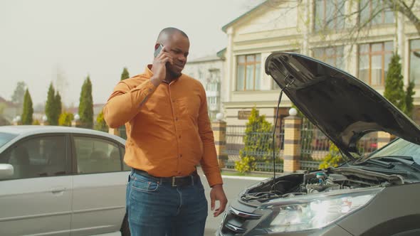 Man Near Broken Car Calling for Roadside Assistance alt