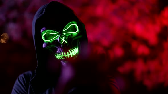 Mysterious Glowing Skull Mask on Face of Enigmatic Man on Street in Night Time alt