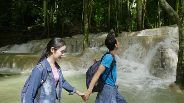 Couple Holding Hand And Walking In Waterfall alt