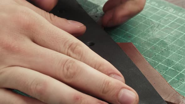 Man Hands Making Hole in Black Leather Belt with Professional Tools Closeup alt