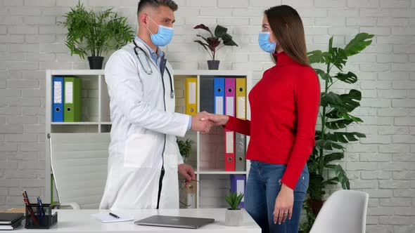 Doctor and patient get up from chairs shake hands after agreeing on treatment alt