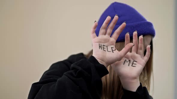 Teenage Girl Covers Her Face with Her Palms with the Inscription HELP ME alt