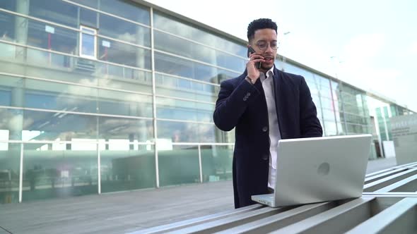 Businessman talking on the phone while using laptop
