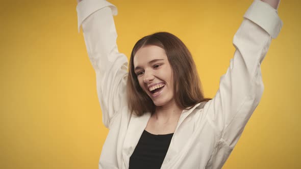 Young Adult Caucasian Woman is Celebrating an Achievement on a Bright Yellow Background alt