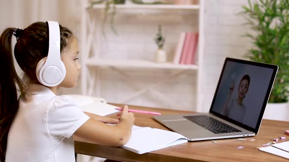 Little Child Girl Using Laptop for Doing School Tasks at Home and Writing Notes.