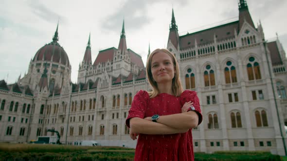 Portrait of Happy Young Lady with Arms Crossed Near Budapest Parliament Building