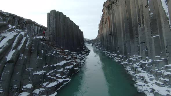 Studlagil canyon with hexagonal basalt columns and turquoise water hidden gem. FPV. alt