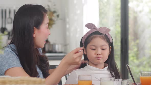 Asian mom and daughter happy talking together while eating bread, drink ...