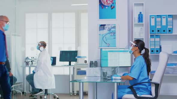 Pushing Disabled Senior Woman in Wheelchair Through Waiting Area alt