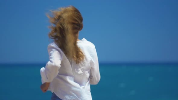 A Young Girl Runs Up To the Cliff Above the Beautiful Sea. Beautifully Develop Hair in the Wind alt