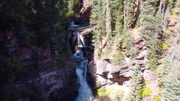 Aerial Through Two Waterfalls in Gorge Surrounded By Pine Trees alt