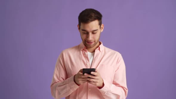 Studio Portrait of Cheerful Young Man Typing Message Using Mobile Phone to Communicate Online alt