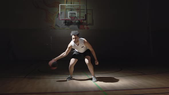 Guy Dribbling Ball in Indoor Basketball Court alt