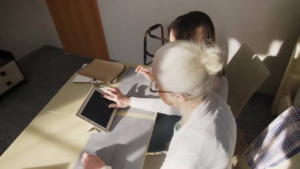 Top View of Senior Woman Using Tablet with Female Volunteer