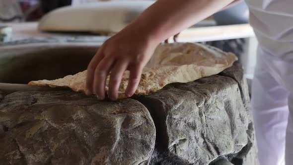 a Woman Baker Removes Fresh Fried Armenian Lavash From a Hot Tonir alt