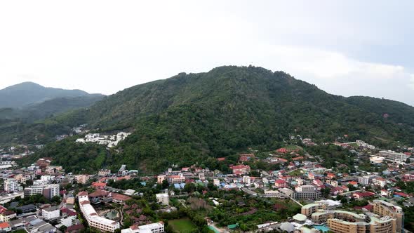 Aerial Flying Towards Forested Hillside Over Buildings In Phuket. Dolly Forward, Establishing Shot alt