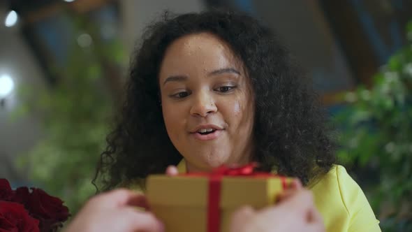 Closeup Portrait of a Beautiful Cute Young Girl Receives a Gift and Shakes It to Find Out What's