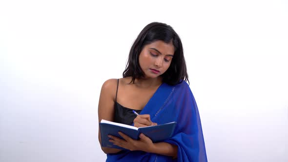 Indian woman in saree writing down notes alt