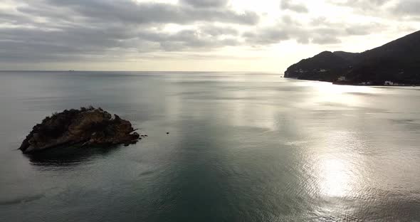One Small Lonely Island on the Ocean Aerial Sun Set Above Mountain Silhouette alt