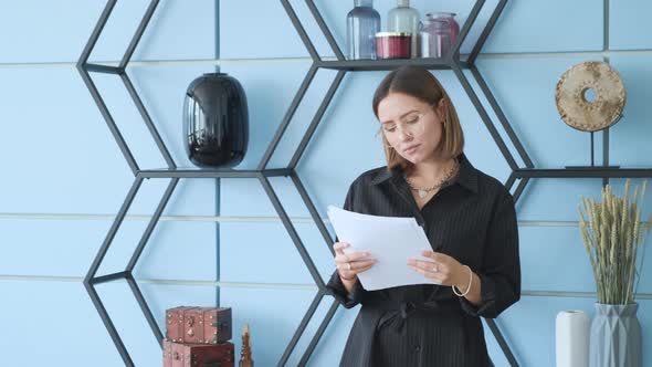 Focused business woman looking on diagrams at home office. Portrait of girl freelancer reading  alt