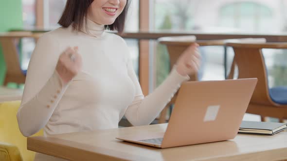 Unrecognizable Satisfied Young Woman Making Victory Gesture and Smiling Sitting in Cafe with Laptop alt