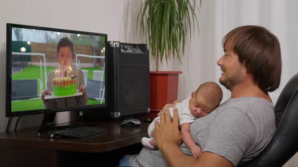 View Over the Shoulder on the Young Woman PC on Which Watching a Video of Small Boy Blowing Candles alt