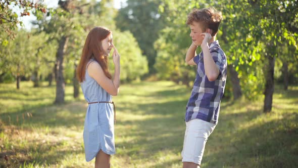 Side View Portrait of Cheerful Relaxed Teenage Couple Grimacing Talking Standing in Summer Spring alt