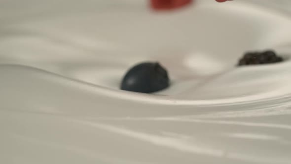 Fresh red-black raspberries and blueberries rain on yogurt in slow motion – Close up