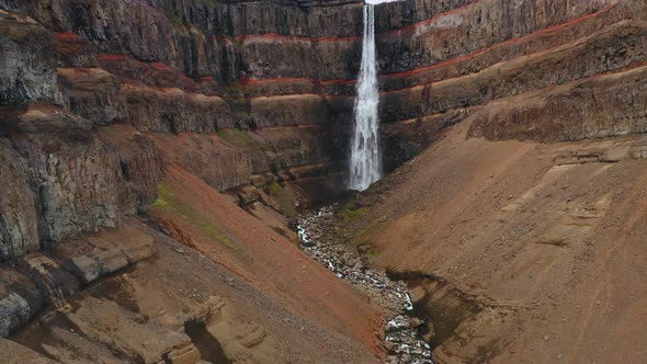 Aerial Static Footage of Hengifoss Waterfall Red Mountain Wall and River in Iceland alt