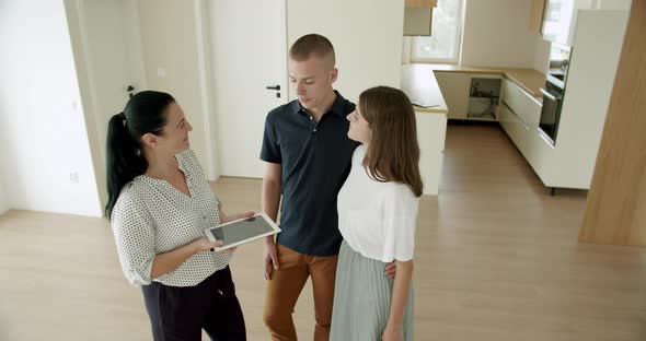 Estate Agent Using Digital Tablet With Couple in New House
