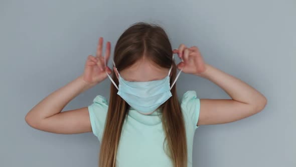 Little girl putting on wearing surgical medical face mask