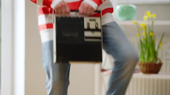 Closeup Vintage Tape Recorder in Female Hands with Joyful Mature Woman Dancing Indoors alt