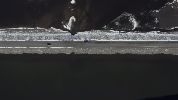 Bird's Eye View of a Car Driving Along a Narrow Road Crossing a Lake alt