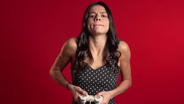 Pretty Latin Girl Playing Video Exciting Game on Tv with Joystick on Red Wall alt