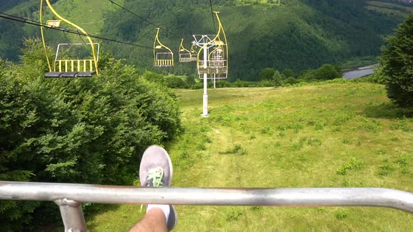 Man Sitting in the Ski Elevator and His Feets Is Shaking Over the Mountain